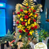 Tall floral standing spray with red and yellow roses and palm fronds