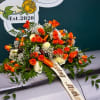 Orange and white rose arrangement with baby's breath on a casket
