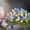 White roses and blue flowers arranged with ribbons on a table