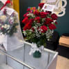 Red rose bouquet in a glass vase with baby's breath and a white ribbon