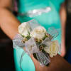 White rose corsage with silver ribbon on a wrist