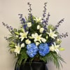 Large floral arrangement with white lilies, blue hydrangeas, and purple flowers