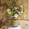 Burlap covered mason jar with daisies, larkspur and spray roses with wispy