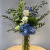 Blue hydrangeas and white roses in a clear glass vase