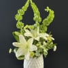 White lilies and green blooms in a white vase
