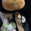 Black teddy bear with a gold bow and floral wrist corsage