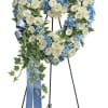Heart-shaped floral wreath with white and blue flowers on a stand