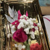 Pink rose boutonniere with white baby's breath on a gold tray
