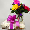 Birthday flower arrangement with cupcakes and a pink topper in a jar vase