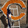 Orange and white floral funeral wreath on a stand with a ribbon