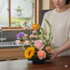 Mixed flower arrangement in a black rectangular vase with a sunflower and pink rose
