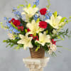 Crisp white lilies and towering blue delphinium spikes create a striking red-white-blue