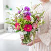 Woman holding a colorful bouquet in a clear glass vase