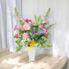 Mixed pink and yellow flower arrangement in a white vase