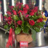 Red roses arranged in a round terracotta pot with a ribbon.