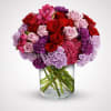Bouquet of red and pink roses with purple carnations in a glass vase