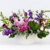 Mixed purple and white floral arrangement in a white bowl vase