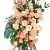 Peach and coral roses take center stage in this tall sympathy arrangement