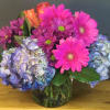 Assorted Brightly colored Blooms in a light Lavendar Vase