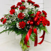 Red carnations and white baby's breath in a clear glass vase with a red ribbon