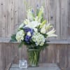 Tall white lilies and soft blue hydrangeas create a calm, refined presence
