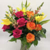Bouquet of pink and orange roses with yellow lilies in a glass vase