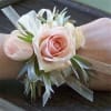 Pink rose wrist corsage with white ribbon and greenery