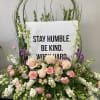 Large floral arrangement with a sign reading "STAY HUMBLE. BE KIND. WORK HARD."