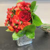 Bouquet of red and orange roses in a square glass vase