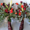 Two floral arrangements in burgundy boots with red and orange flowers