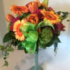 Bouquet of orange and pink flowers in a tall glass vase with a green ribbon