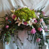 Large floral spray with pink roses, white lilies, and green blooms