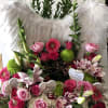 Pink and red floral arrangement with white feather wings and heart tags