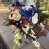Handheld bouquet with blue, white, and orange flowers and trailing orchids