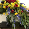 Large standing arrangement of red and yellow roses with blue flowers in a black vase