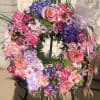 Colorful floral wreath with roses, hydrangeas, and ribbon on a stand