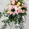 Pink rose and yellow flower standing spray with trailing greenery and ribbon