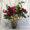 Pink and burgundy roses with carnations in a glass vase with a gold bow