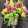 Colorful bouquet of roses, gerbera daisies, lilies, and hydrangeas in a silver vase