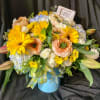 Peaches and yellow seasonal blooms in a custom vase.