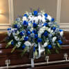 A dignified blue-and-white casket spray that offers a cool-toned, respectful tribute for