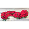 Heart-shaped arrangement of red roses with greenery