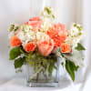 Peach and white roses arranged in a clear glass vase