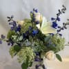 White roses and blue flowers in a clear glass vase