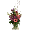 Tall mixed bouquet with pink gerberas, red roses, and purple orchids in a glass vase