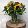 Sunflowers and red roses arranged in a clear glass vase