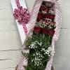 Bouquet of red roses in heart-patterned wrap beside a white gift box with pink ribbon