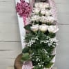 Bouquet of pale pink roses wrapped in heart-patterned paper with a pink bow