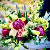 Hand-tied bouquet with bright pink roses, yellow blooms, lilies and mixed flowers wrapped in white paper