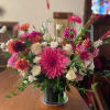 Low glass vase of pink dahlias and white roses with mixed bright blooms on a wooden table